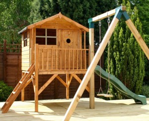 Garden playhouse on stilts with a swing and slide attached.